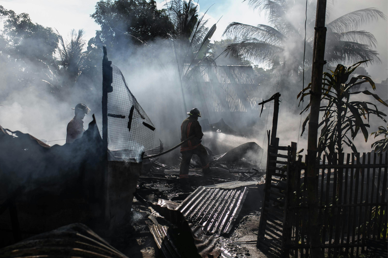 Destruction from fire, people walking through rubble of homes.
